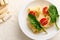 Flat lay of a vegetarian uncooked traditional Italian whole wheat pasta with halves of tomato and green spinach leaves on a