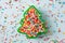 Flat lay view of Christmas tree shaped cookie cutter filled with rainbow sugar sprinkles.