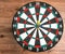 Flat lay view of a dartboard with three darts in the bull`s eye. Well-aimed dart throwing.
