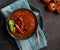 A flat lay view of a large bowl of roasted red pepper soup garnished with roasted red peppers and basil.