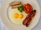 Flat lay view of a western fried breakfast â€“ bacon and eggs, sausages and fried tomato
