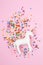 Flat lay with white unicorn and colorful glitter over the pink background. Magic surreal, fairy tale style. Minimal composition