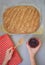 Flat lay of woman hands holding jar of Raspberry jam and freshly baked bread on table