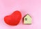 Flat layout of wooden model house and red heart shape pillow  isolated  on pink  background with copy space, dream home or home