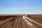 Flat plain with brown soil and a rustic road. Environment for off road adventure. Bolivian Andes desert.