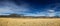 Flat prairie leading to mountains under a blue sky