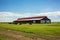 flat roof barn on prairie, livestock grazing nearby
