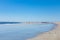 Flat, sandy shoreline with wide tide pools reflecting a bright blue sky, distant beachcombers, Tybee Island Georgia