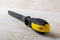 Flat steel file with black yellow rubber handle on a white wooden surface. Rasp tool for processing of wood and metals. Repair and