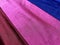 Flat surface of maroon, pink and blue shiny fabric