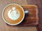 Flat white coffee with latte art on wooden saucer