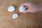 Flat white stones lie on a natural wooden background, woman`s hand holds one object, background with space, concept of spa