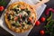 Flatbread pizza garnished with fresh arugula on wooden pizza board, top view. Dark stone background. Person picking slice of pizza