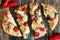 Flatbread pizza with mozzarella, tomatoes, spinach, artichokes, over rustic wood