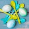 Flatlay, blue and green colored easter eggs and egg spoons on bl