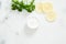 Flatlay organic dermatology cosmetic hygienic cream in glass jar, parsley, citrus lemon on white marble background. Skincare