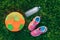 Flatlay with pair of pink girl sneakers shoes, child fabric soft soccer ball and bottle of water in green grass