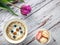 Flatlay of violet tulip with bowl of cereals with berries and little bowl with colored cakes