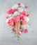 Flatlay waffle sweet ice cream cone with pink tulips and roses blossom flowers over white wood background, top view