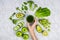 Flatlay with woman`s hand reaching for green juice surrounded by green fruits and vegetables