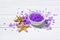 Flavored purple sea salt crystals with violet flower and starfishes on white