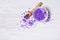 Flavored purple sea salt crystals with violet flower and wooden scoop on white