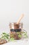 Flax seeds in glass jar with wooden spoon and natural elements leaves and bark on grey background