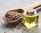 Flax seeds or linseeds in spoon and bowl with glass of linseed oil