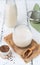 Flaxseed milk in glass on sackcloth, milk bottle, flax seeds, mint leaf, sieve. Close up