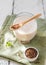 Flaxseed milk in glass with wooden teaspoon on light green napkin, flax seeds, mint leaf.