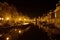 Fleet of boats in a canal in front of a picturesque row of houses at night: Leiden