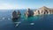 Fleet of yachts sailing in the sea against the Cabo San Lucas arch on a sunny day