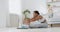 Flexibility training. Young black lady stretching at home, sitting on floor and reaching to feet