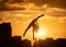 Flexible acrobat doing handstand on the cityscape background during dramatic sunset. Concept of willpower, control and