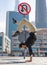 Flexible Acrobat keep balance on the hands with blurred Dubai cityscape and traffic sign U-Turn is prohibited. Concept