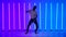 Flexible African American man dancing in the studio against the backdrop of multicolored neon lights. Latin dance. Salsa