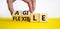 Flexible and agile symbol. Concept words Flexible and agile on wooden cubes. Businessman hand. Beautiful yellow table white