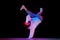 Flexible, artistic young man, breakdancer in motion, performing isolated over black studio background in neon light