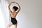 Flexible asian ballet dancer stretching on white wall studio