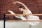 Flexible beautiful woman doing ballet pose in front of the barre