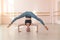 Flexible Caucasian girl stands on her head in a dance class. The girl does yoga. . Woman dancing breakdance on the