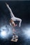 Flexible circus artist - female acrobat doing handstand on the back and smoker background. Concept of individuality and