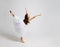 Flexible cute little girl gymnast doing acrobatic exercise. Child dancing in princess dress isolated on gray background