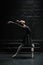 Flexible female dancer stretching in the black room