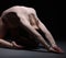 Flexible female gymnast exercising in dark studio