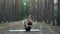 flexible female practices yoga, performs ubhaya padangusthasana at pine forest