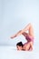 Flexible girl gymnast in beige leotard is performing complex elements of gymnastics while posing isolated on white