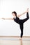Flexible girl, yogi performing stance in Lord of dance pose. Female in black on white background. Vertical side portrait