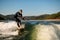 flexible man in wetsuit on wakesurf skilfully riding on splashing river wave