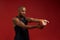 Flexible muscles. Portrait of young and strong afro american man in sports clothing stretching arms while standing